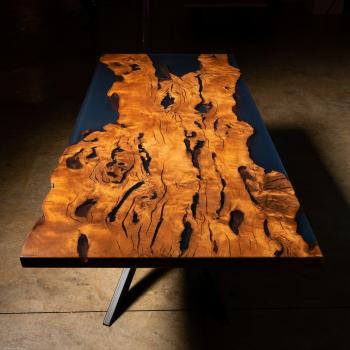 Ein Esstisch aus Massivholz mit lebender Kante umhüllt in blau schimmernden Kunstharz