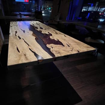 Ein wunderschöner Tisch aus einer sehr lebendigen, kontrastreichen Hainbuche, umhüllt und schwebend im transparenten Gewand des Epoxidharzes, getragen durch ein Gestell aus einem gehärteten 2 cm starken Glas.