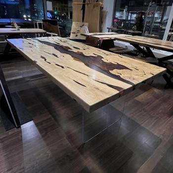 Preview: Ein wunderschöner Tisch aus einer sehr lebendigen, kontrastreichen Hainbuche, umhüllt und schwebend im transparenten Gewand des Epoxidharzes, getragen durch ein Gestell aus einem gehärteten 2 cm starken Glas.