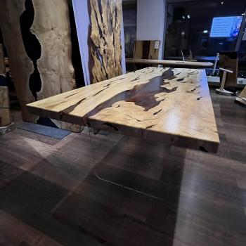 Ein wunderschöner Tisch aus einer sehr lebendigen, kontrastreichen Hainbuche, umhüllt und schwebend im transparenten Gewand des Epoxidharzes, getragen durch ein Gestell aus einem gehärteten 2 cm starken Glas.