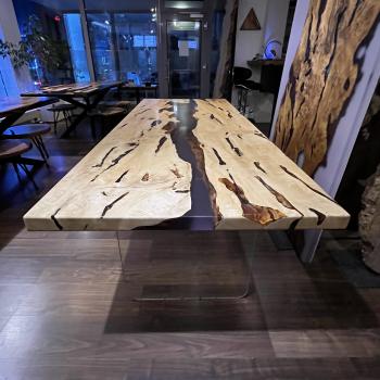 Ein wunderschöner Tisch aus einer sehr lebendigen, kontrastreichen Hainbuche, umhüllt und schwebend im transparenten Gewand des Epoxidharzes, getragen durch ein Gestell aus einem gehärteten 2 cm starken Glas.