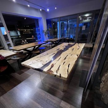 Ein wunderschöner Tisch aus einer sehr lebendigen, kontrastreichen Hainbuche, umhüllt und schwebend im transparenten Gewand des Epoxidharzes, getragen durch ein Gestell aus einem gehärteten 2 cm starken Glas.