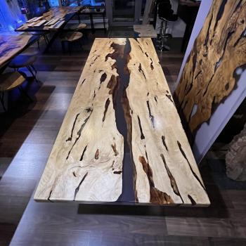 Ein wunderschöner Tisch aus einer sehr lebendigen, kontrastreichen Hainbuche, umhüllt und schwebend im transparenten Gewand des Epoxidharzes, getragen durch ein Gestell aus einem gehärteten 2 cm starken Glas.