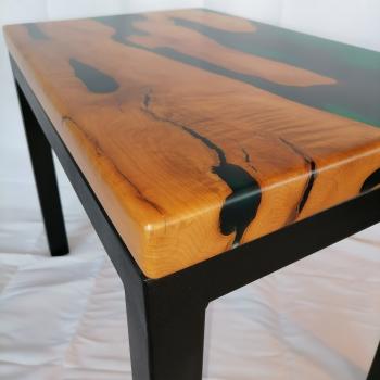 Couchtisch aus Massivholz und Epoxid auf einem Metallgestell.