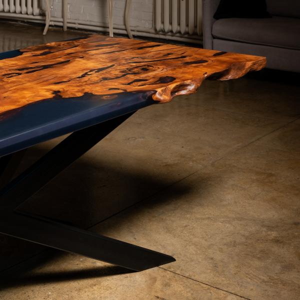Ein Esstisch aus Massivholz mit lebender Kante umhüllt in blau schimmernden Kunstharz